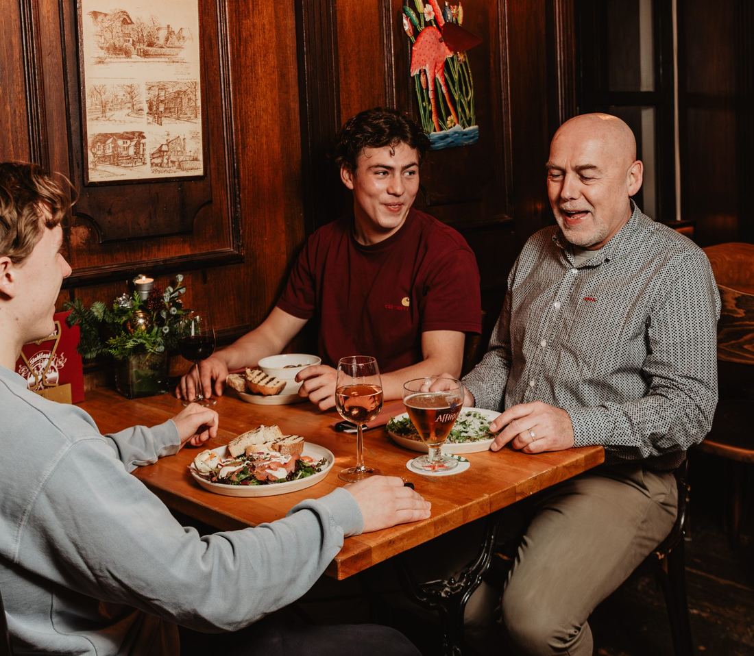 Gasten van drie generaties eten en drinken samen aan tafel bij Stadtlander